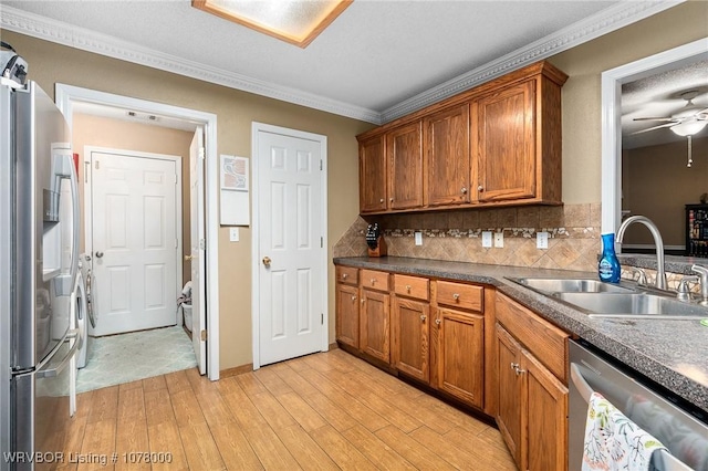 kitchen with appliances with stainless steel finishes, backsplash, sink, light hardwood / wood-style flooring, and washing machine and dryer