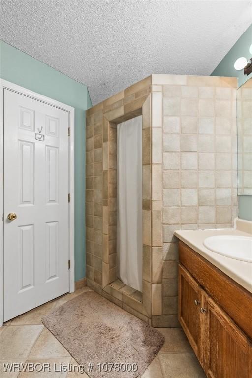 bathroom with vanity, a textured ceiling, tile walls, and tile patterned flooring