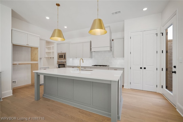 7627 Woodbine Ln, Fort Smith, AR 72916 - kitchen featuring appliances with stainless steel finishes, light wood-style flooring, light countertops, a center island with sink, and recessed lighting