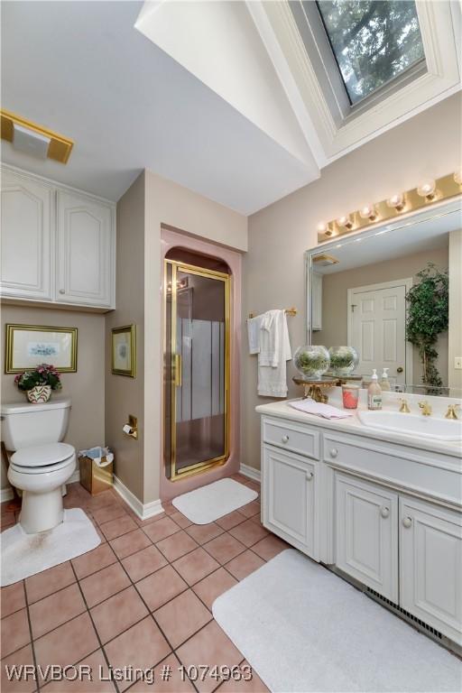 bathroom with tile patterned flooring, lofted ceiling with skylight, toilet, a shower with door, and vanity