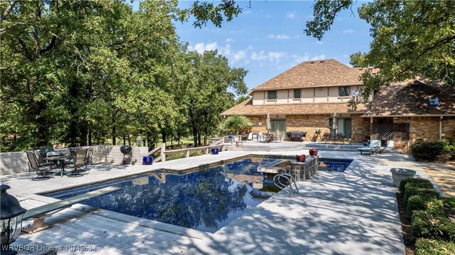 view of swimming pool with a patio area and a diving board