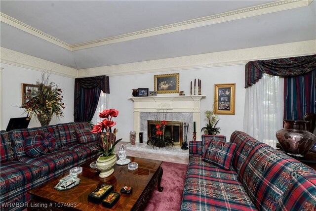 living room featuring lofted ceiling, crown molding, carpet floors, and a fireplace