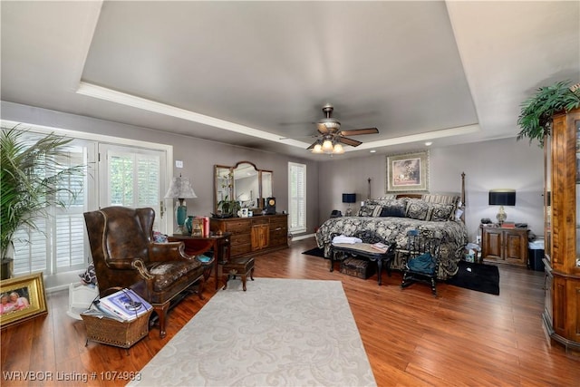 bedroom with a tray ceiling, ceiling fan, and hardwood / wood-style floors