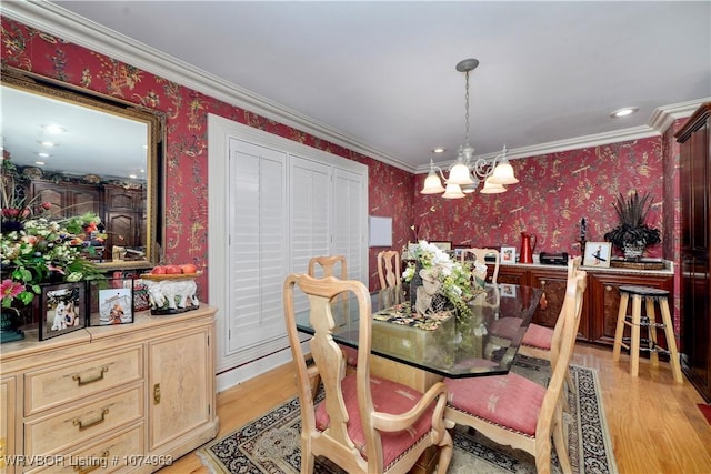 dining area with light hardwood / wood-style floors, ornamental molding, and an inviting chandelier