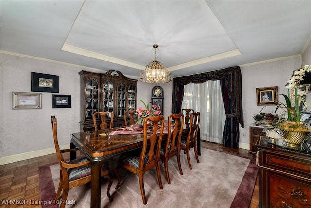 dining room featuring dark parquet flooring, ornamental molding, a tray ceiling, and an inviting chandelier