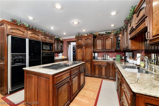 kitchen with sink, a center island, crown molding, light hardwood / wood-style floors, and black appliances