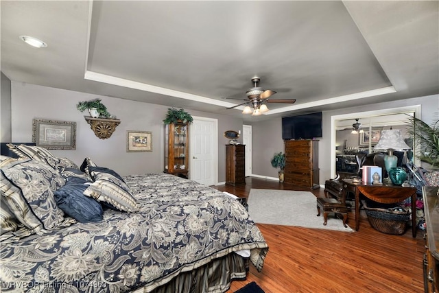 bedroom with a raised ceiling, ceiling fan, and hardwood / wood-style flooring