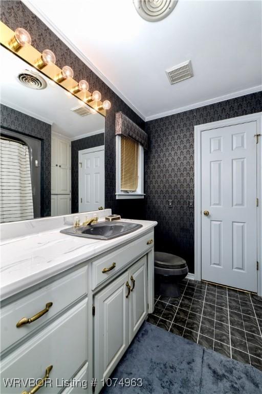 bathroom with tile patterned floors, crown molding, vanity, and toilet