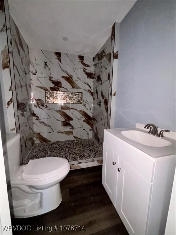 bathroom with vanity, wood-type flooring, toilet, and tiled shower