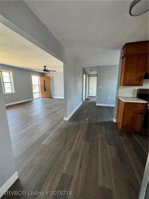 unfurnished living room featuring ceiling fan and dark hardwood / wood-style flooring