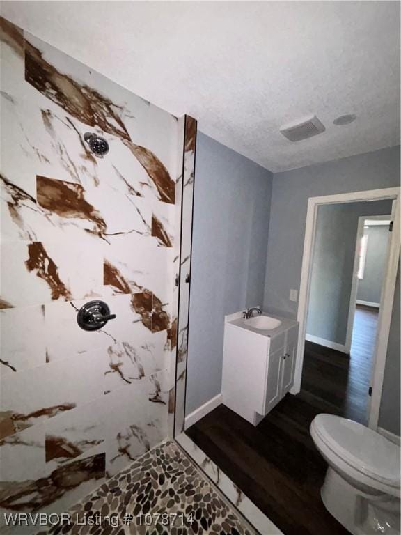 bathroom with walk in shower, toilet, a textured ceiling, vanity, and hardwood / wood-style floors