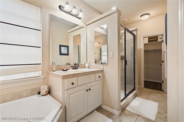 bathroom featuring plus walk in shower, vanity, and tile patterned floors