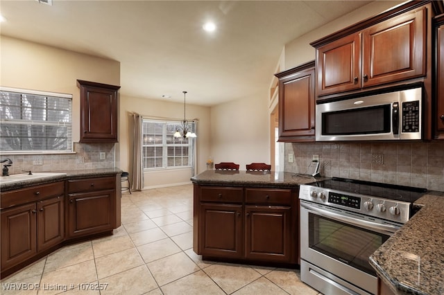 kitchen with backsplash, light tile patterned floors, stainless steel appliances, and an inviting chandelier