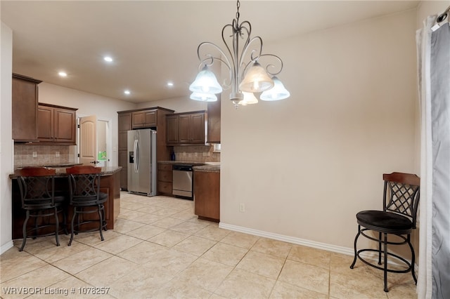 kitchen featuring pendant lighting, backsplash, appliances with stainless steel finishes, and an inviting chandelier