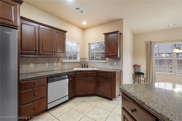 kitchen featuring backsplash, sink, light tile patterned floors, and stainless steel appliances