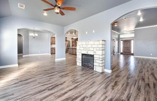 unfurnished living room featuring a fireplace, ceiling fan with notable chandelier, hardwood / wood-style flooring, and vaulted ceiling