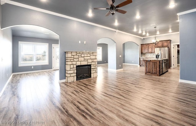 unfurnished living room with a fireplace, light hardwood / wood-style flooring, ceiling fan, and ornamental molding