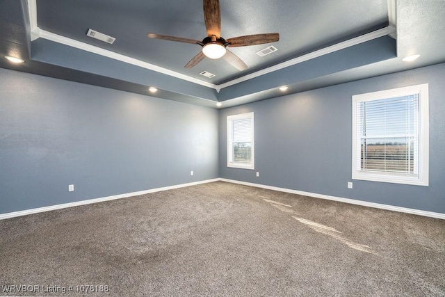 carpeted empty room with ceiling fan, a raised ceiling, and crown molding