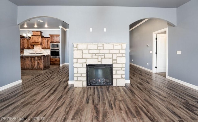 unfurnished living room featuring a stone fireplace and dark hardwood / wood-style floors