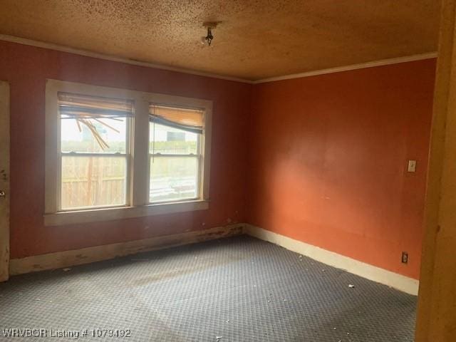 carpeted spare room with a textured ceiling, baseboards, and ornamental molding