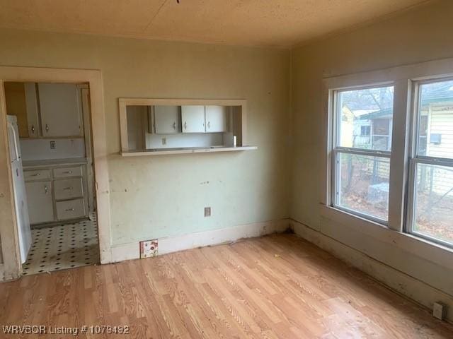 unfurnished dining area featuring light wood-style flooring and baseboards