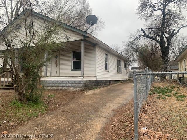 view of property exterior with a porch and fence