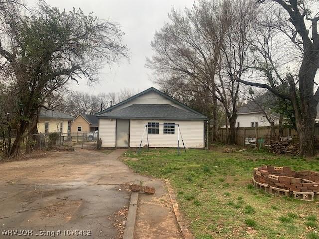 rear view of house with a lawn and fence