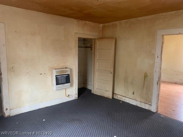 empty room featuring dark colored carpet and heating unit