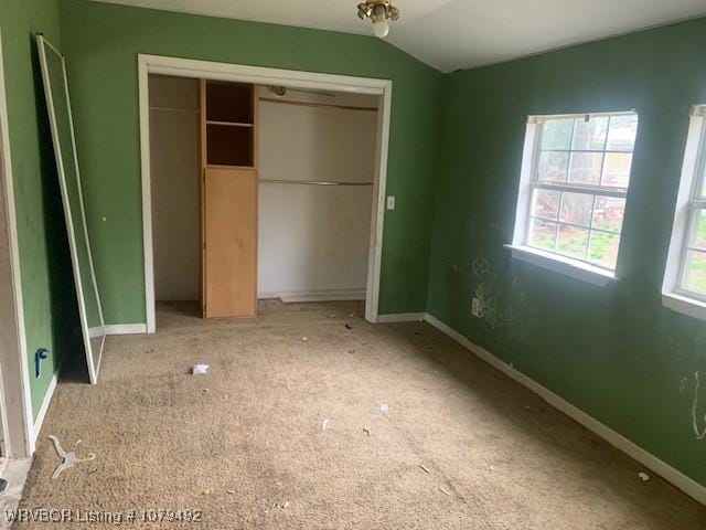 unfurnished bedroom with carpet, lofted ceiling, baseboards, and a closet