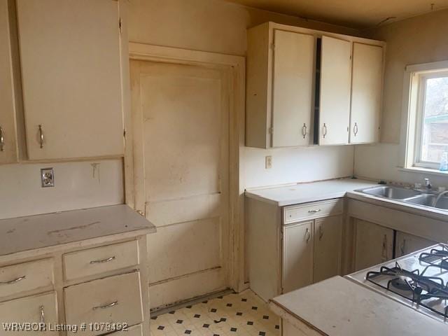 kitchen with a sink, cooktop, light floors, and light countertops