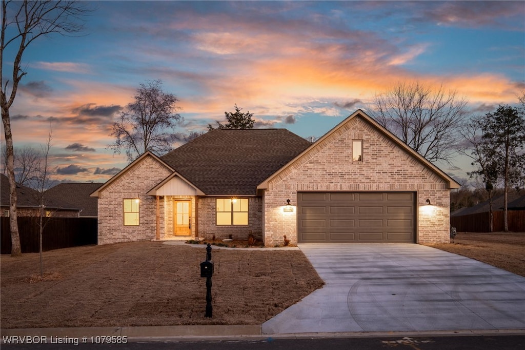 view of front of house with an attached garage, brick siding, driveway, and roof with shingles