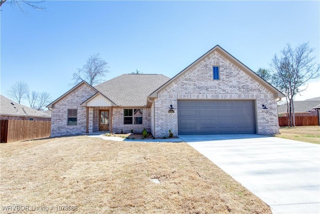 view of front of property featuring driveway, brick siding, fence, and a garage