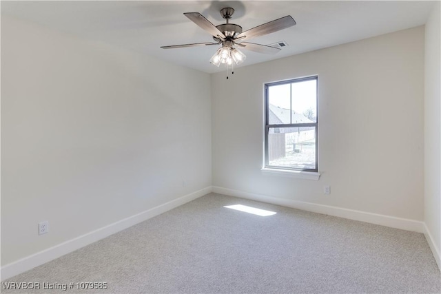 carpeted spare room with a ceiling fan and baseboards