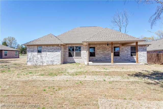 back of house featuring a patio area, fence, brick siding, a shingled roof, and a yard