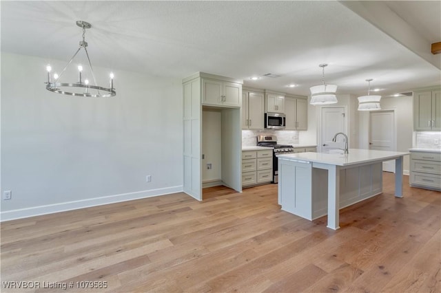 kitchen with tasteful backsplash, appliances with stainless steel finishes, a chandelier, and light wood-type flooring