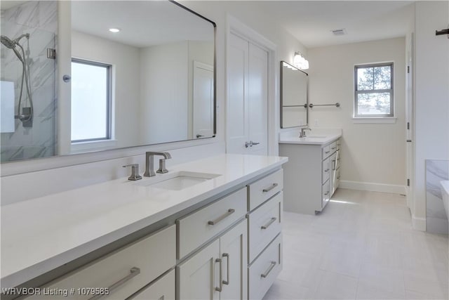 full bathroom with a sink, two vanities, baseboards, and a shower stall