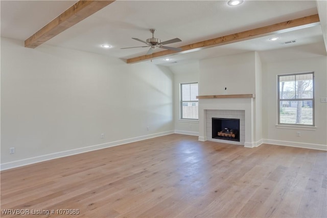 unfurnished living room featuring baseboards, visible vents, and beam ceiling