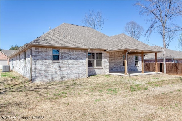 rear view of house featuring a patio, fence, central AC, and roof with shingles