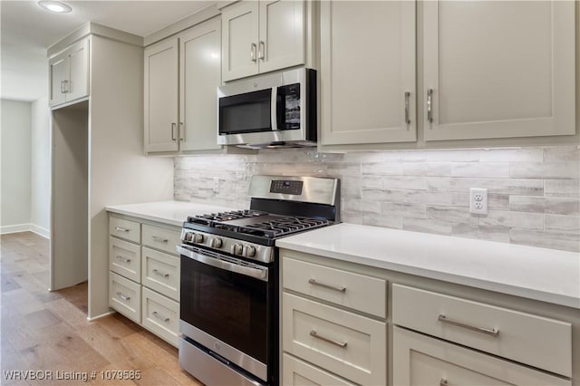 kitchen with light wood-style floors, light countertops, stainless steel appliances, and backsplash