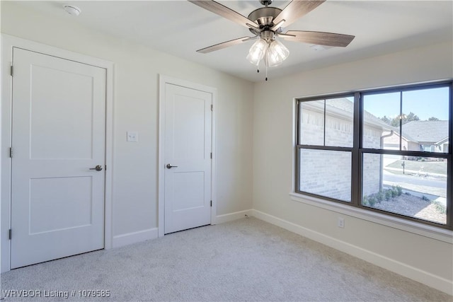 unfurnished bedroom featuring light carpet, baseboards, and ceiling fan