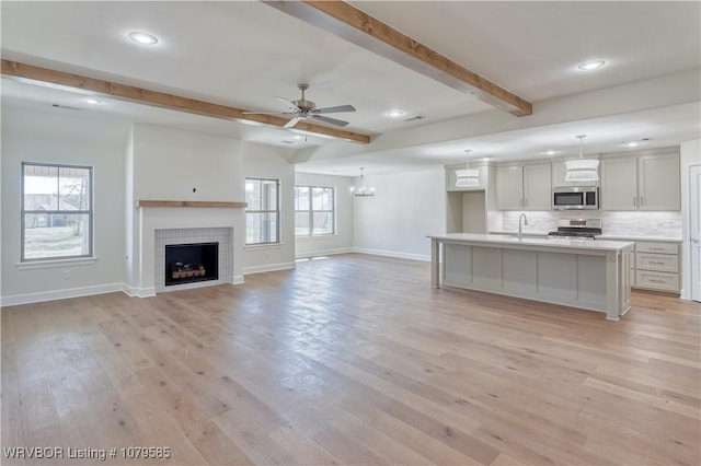 kitchen with a sink, stainless steel appliances, a healthy amount of sunlight, and beamed ceiling