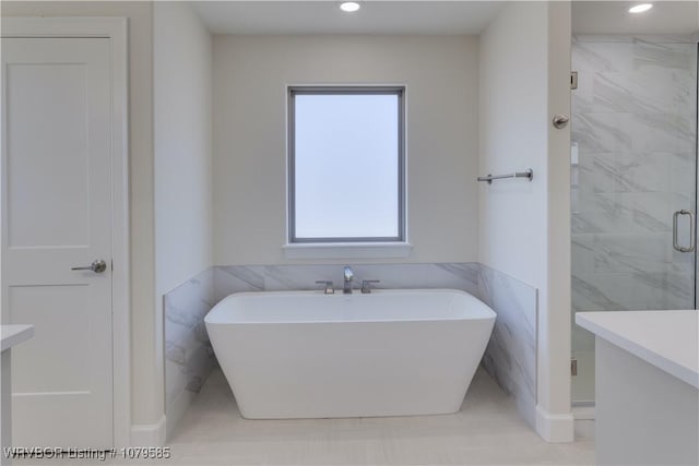 bathroom featuring a stall shower, a freestanding bath, recessed lighting, and tile walls