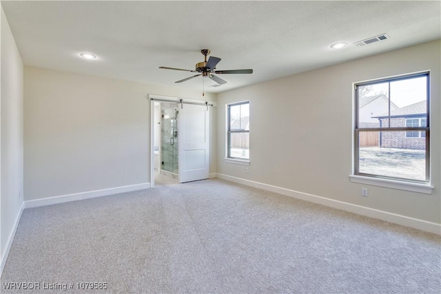 spare room with light colored carpet, recessed lighting, baseboards, a barn door, and visible vents