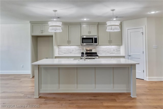 kitchen featuring light countertops, stainless steel appliances, light wood finished floors, and tasteful backsplash