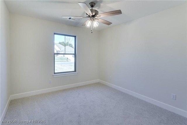 carpeted spare room featuring baseboards, visible vents, and a ceiling fan