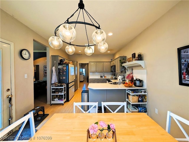 kitchen featuring decorative backsplash, gray cabinetry, sink, light hardwood / wood-style floors, and hanging light fixtures