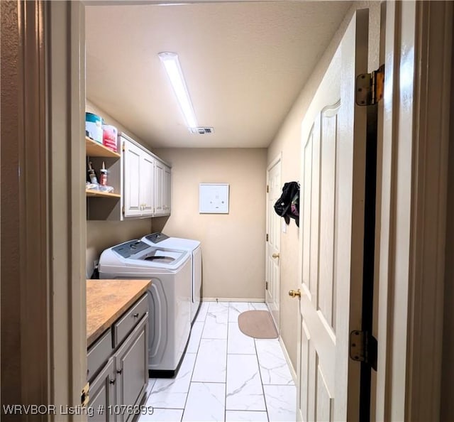 laundry room featuring washing machine and clothes dryer and cabinets