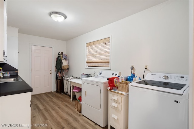 washroom featuring cabinets, light hardwood / wood-style flooring, washer and clothes dryer, and sink