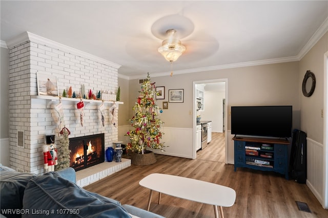 living room featuring hardwood / wood-style floors, a brick fireplace, ceiling fan, and ornamental molding