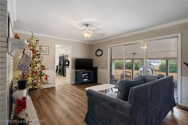 living room with hardwood / wood-style flooring, ceiling fan, a fireplace, and crown molding